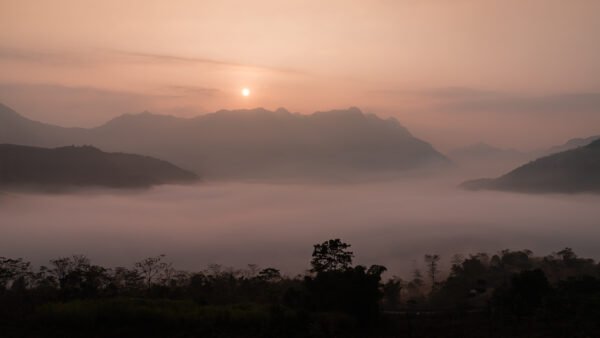 Sunrise in Ha Giang vietnam with mountains fog and orange sun and clouds
