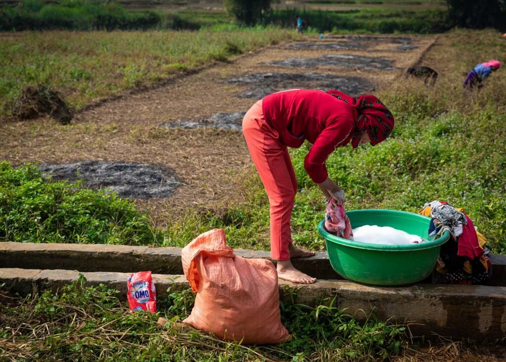 vietnamese woman doing laundry in field washing clothes in a bowl