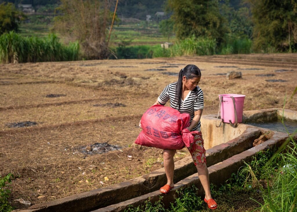 vietnamese woman doing laundry in a field with big bag of clothes